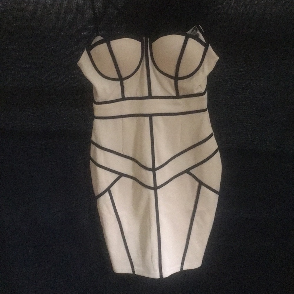 Short nude dress with black straps and detailing.